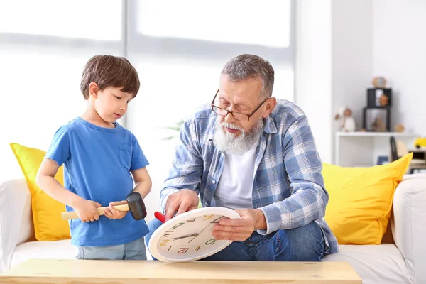 Grandfather teaching little boy to repair clock at home