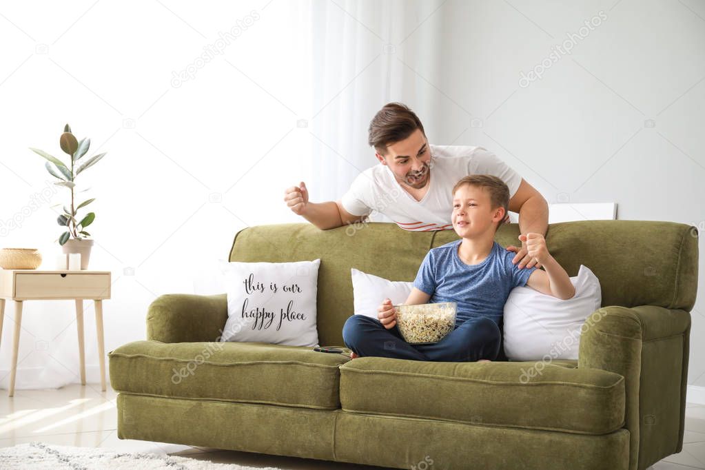 Father with son watching sports on TV at home