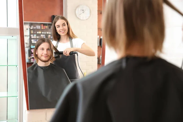 Відбиття жіночого перукаря, що працює з клієнтом в салоні — стокове фото