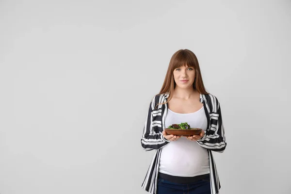 Mulher grávida bonita com salada saudável no fundo branco — Fotografia de Stock