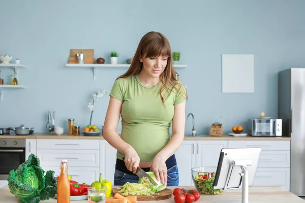 Молода вагітна жінка готує на кухні — стокове фото