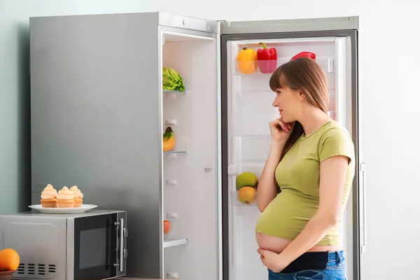 Mulher grávida bonita escolhendo comida no frigorífico da cozinha — Fotografia de Stock