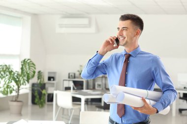 Yakışıklı erkek mimar ofiste telefonla konuşuyor