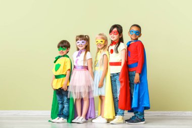 Renkli duvara yakın süper kahramanlar gibi giyinmiş sevimli küçük çocuklar