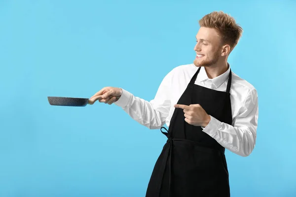 Красивий чоловічий шеф-кухар зі сковородою на кольоровому фоні — стокове фото