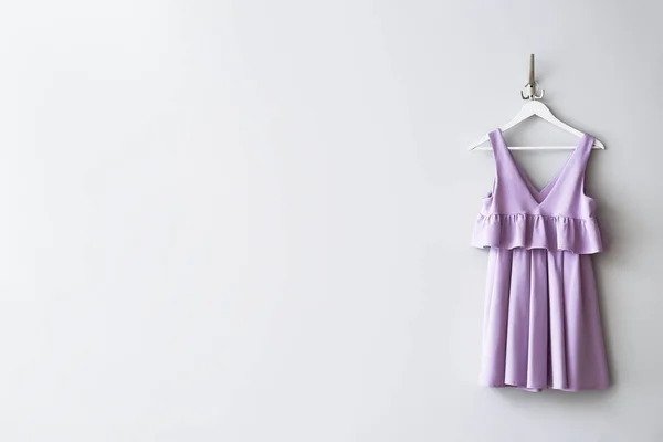 Hanger with clothes on white wall — Stock Photo, Image