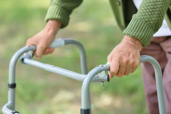 Elderly man with walking frame in park, closeup