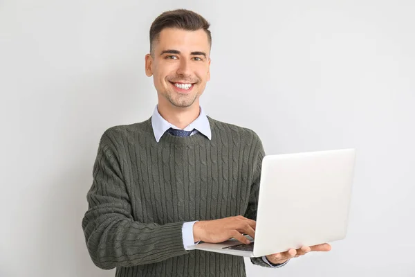 Schöner männlicher Lehrer mit Laptop auf weißem Hintergrund — Stockfoto