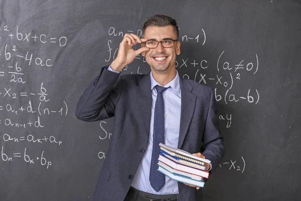 Handsome math teacher near blackboard in classroom — Stock Photo, Image