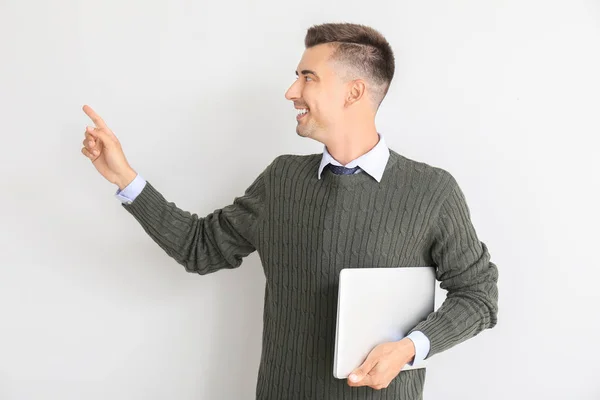 Guapo profesor masculino con portátil apuntando a algo sobre fondo blanco — Foto de Stock