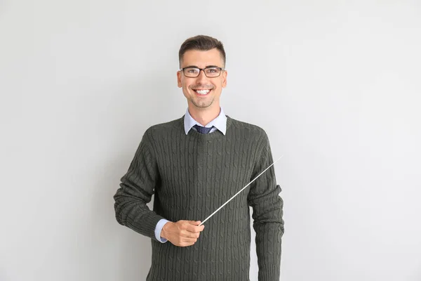 Knappe mannelijke leraar met pointer op witte achtergrond — Stockfoto
