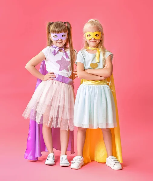 Schattige kleine meisjes gekleed als superhelden op kleur achtergrond — Stockfoto