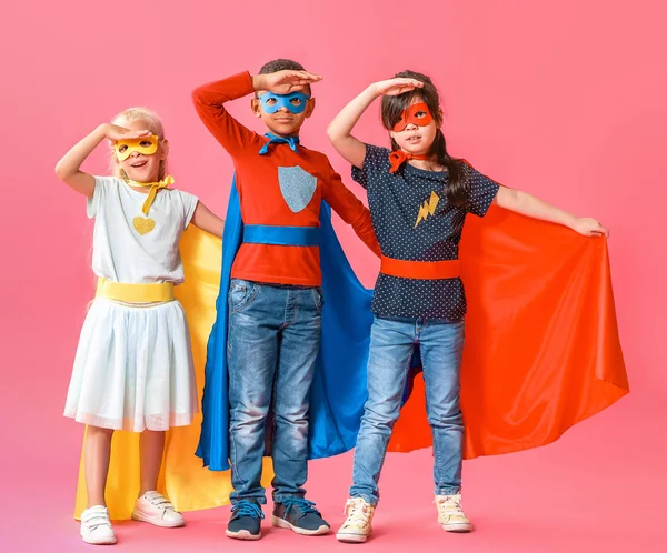 Lindos niños pequeños vestidos como superhéroes en el fondo de color — Foto de Stock