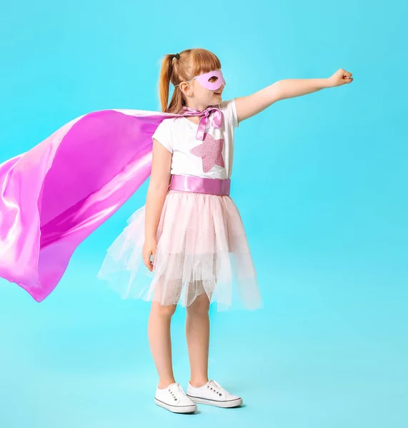 Cute little girl dressed as superhero on color background — Stock Photo, Image