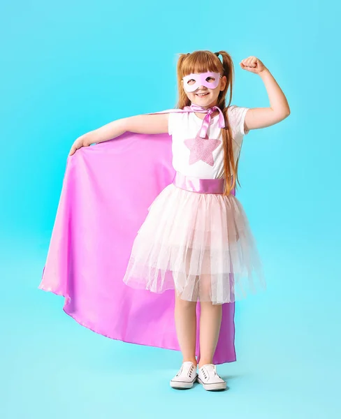 Симпатична маленька дівчинка одягнена як супергерой на кольоровому фоні — стокове фото