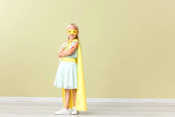 Linda niña vestida como superhéroe cerca de la pared de color —  Fotos de Stock