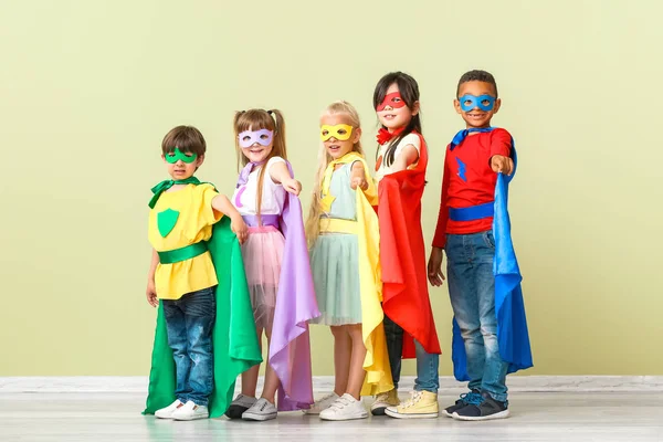 Lindos niños pequeños vestidos como superhéroes cerca de la pared de color — Foto de Stock