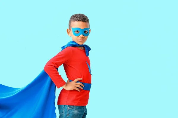 Cute African-American boy dressed as superhero on color background — Stock Photo, Image