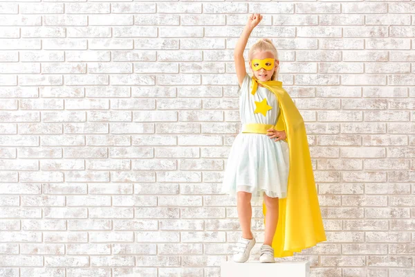 Linda niña vestida como superhéroe cerca de la pared de ladrillo — Foto de Stock