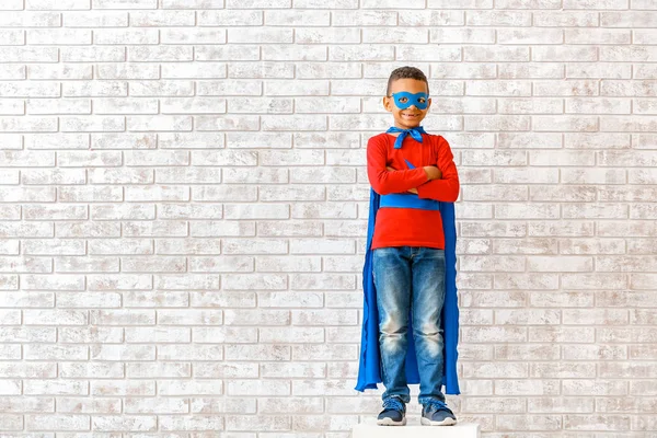 Cute African-American boy dressed as superhero near brick wall — Stock Photo, Image