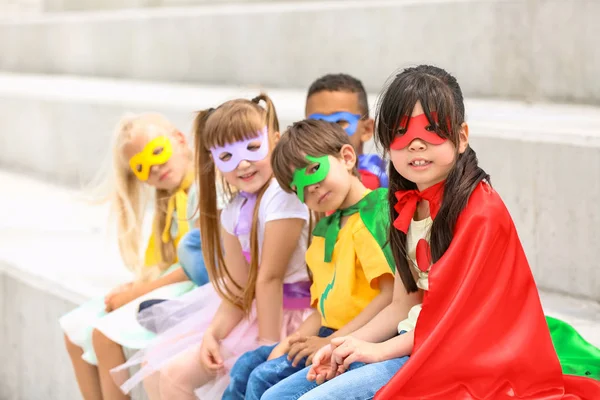 Cute little children dressed as superheroes sitting on stairs outdoors — Stock Photo, Image