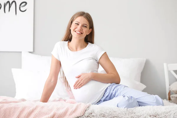 Красивая беременная женщина в спальне — стоковое фото