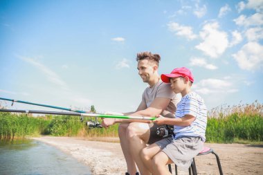 Baba ve oğul nehirde birlikte balık tutuyorlar.