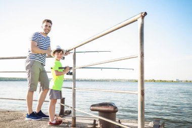 Baba ve oğul nehirde birlikte balık tutuyorlar.