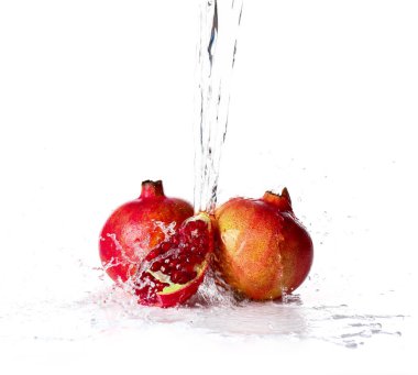 Beyaz arka plana karşı olgun nar üzerine su dökme
