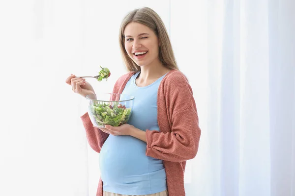 Mooie zwangere vrouw die thuis salade eet — Stockfoto