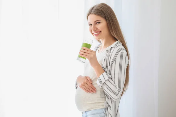 Mooie zwangere vrouw die smoothie thuis drinkt — Stockfoto