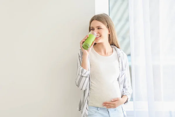 Όμορφη έγκυος γυναίκα πίνοντας χυμό στο σπίτι — Φωτογραφία Αρχείου