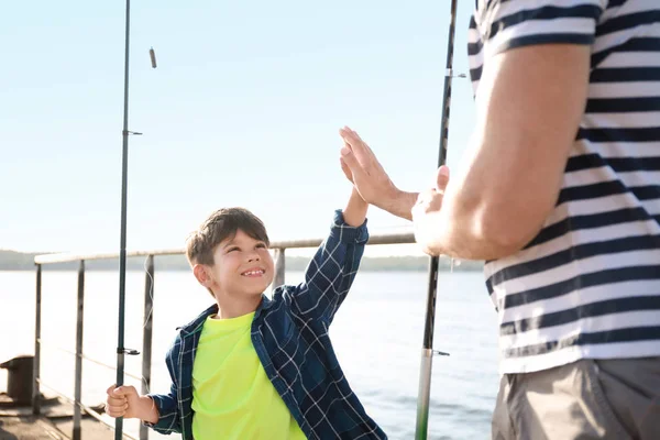 Pai e filho dando uns aos outros high-five enquanto pescavam juntos no rio — Fotografia de Stock