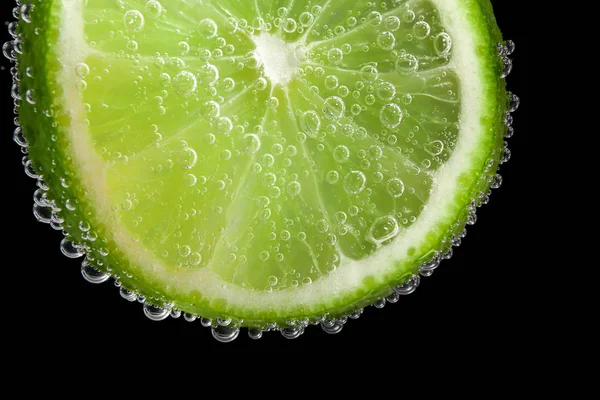 Ripe lime slice in water, closeup — Stock Photo, Image