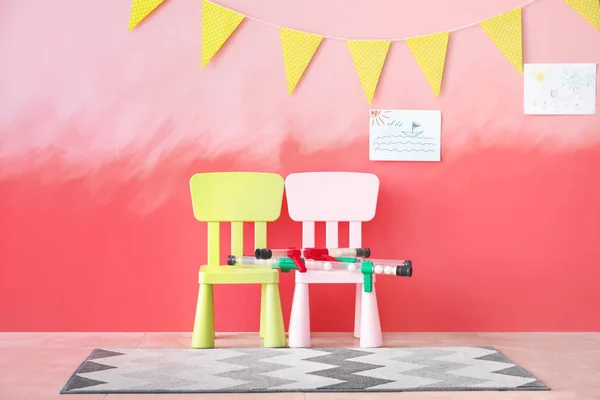 Chairs with pogo sticks near color wall in children's room — Stock Photo, Image