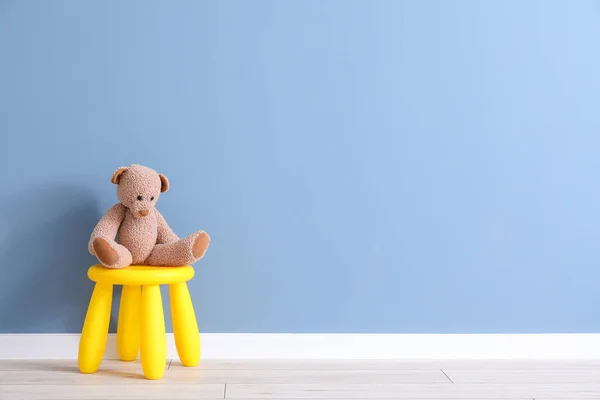 Stołek z zabawką niedźwiedzia w pobliżu koloru ściany w pokoju dziecięcym — Zdjęcie stockowe