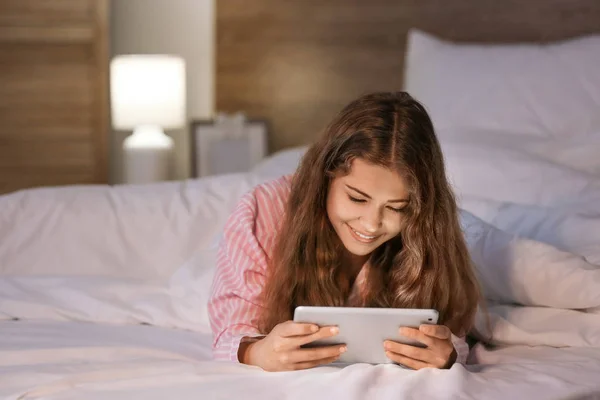 Mladá dívka s tabletovým počítačem v noci v posteli — Stock fotografie