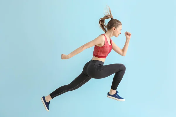 Jumping sporty woman on light color background