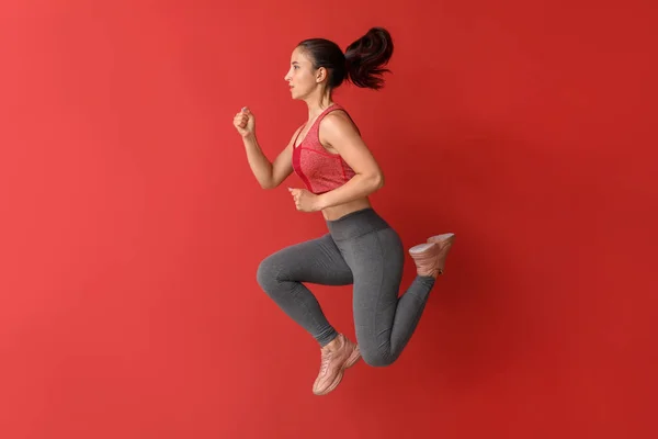 Springen sportliche Frau auf farbigem Hintergrund — Stockfoto