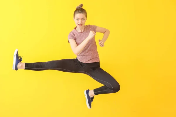 Jumping sporty woman on color background — Stock Photo, Image