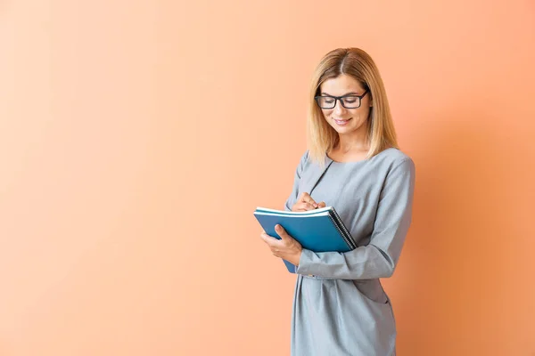 Schöne weibliche Lehrerin auf farbigem Hintergrund — Stockfoto