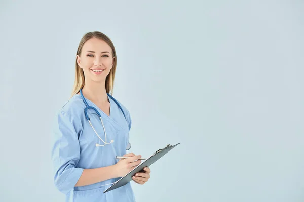 Infermiera femminile con stetoscopio e appunti su sfondo a colori — Foto Stock