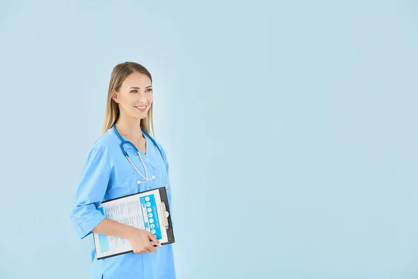 Krankenschwester mit Stethoskop und Klemmbrett auf farbigem Hintergrund — Stockfoto