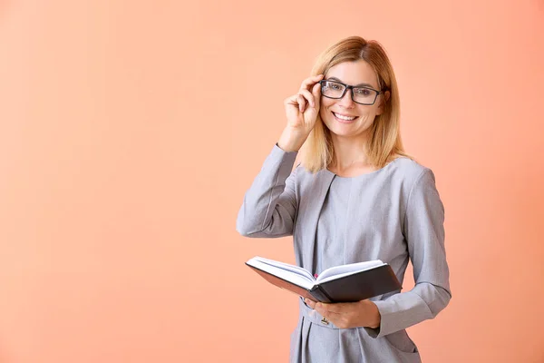 Bella insegnante femminile con libro su sfondo a colori — Foto Stock