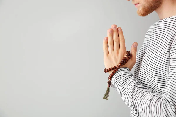 Religious young man praying to God on light background — Stock Photo, Image