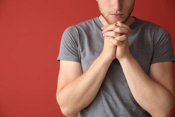 Religious young man praying to God on color background — Stock Photo, Image