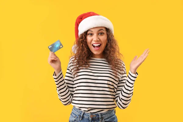 サンタ帽子と色の背景にクレジットカードで幸せなアフリカ系アメリカ人の女性 — ストック写真