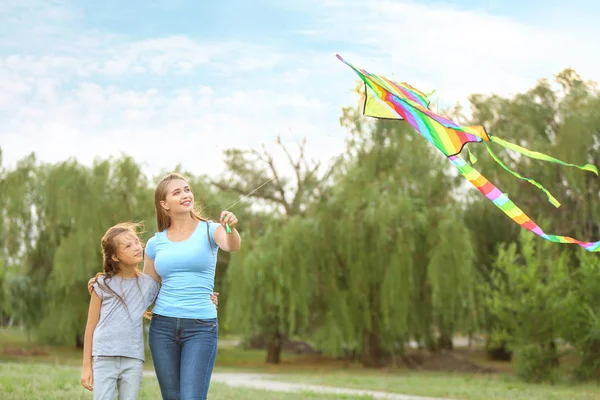 Ung kvinna med liten dotter flygande kite utomhus — Stockfoto