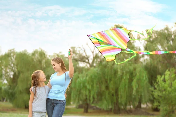 Ung kvinna med liten dotter flygande kite utomhus — Stockfoto