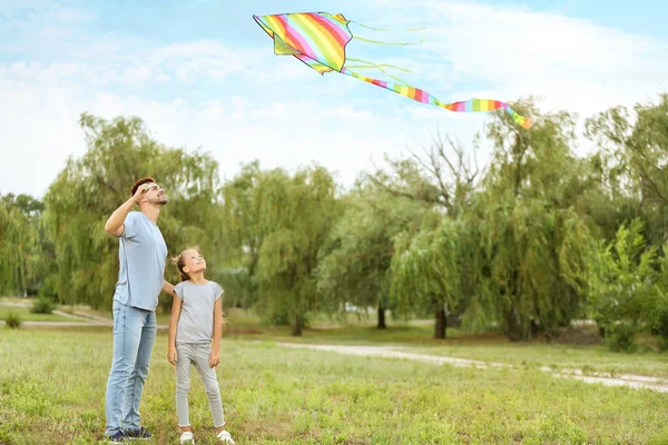 Young man with little daughter flying kite outdoors — Stock Photo, Image